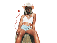 a woman in a cowboy hat sitting on a wooden stump